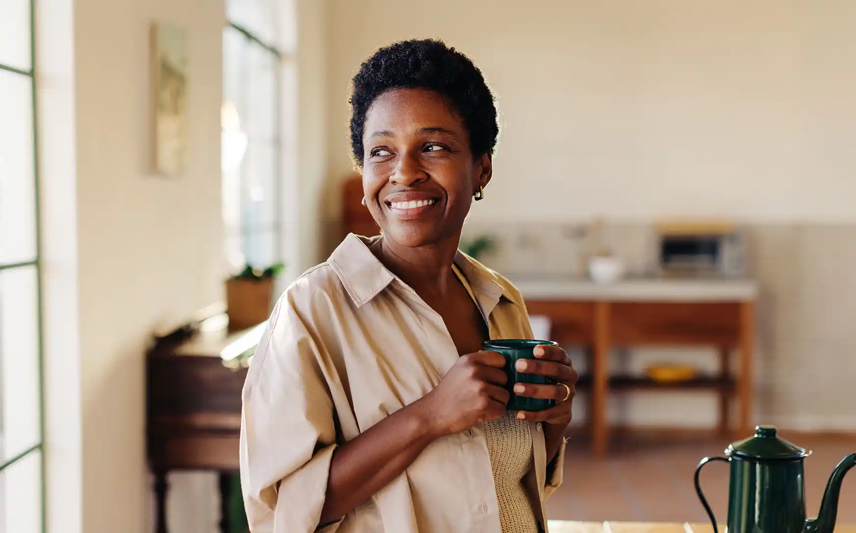 women smiling, holding a cup of coffee