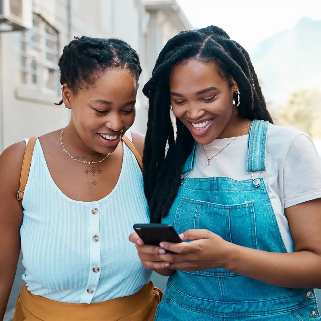 two young women chatting while looking at a phone